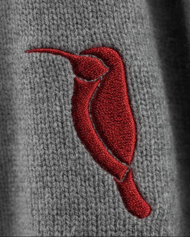 Red embroidered hummingbird on a gray fabric background