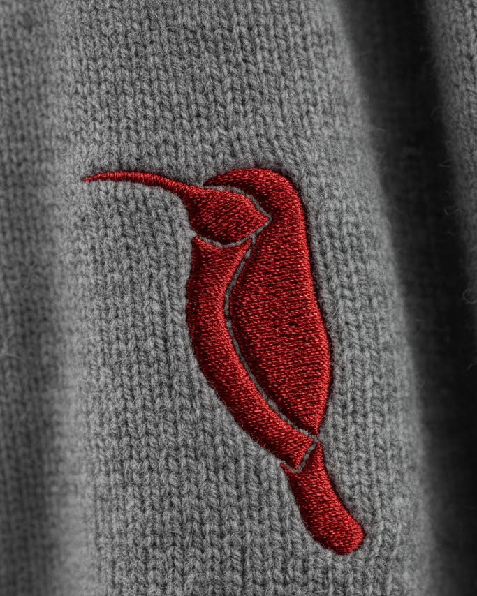 Red embroidered hummingbird on a gray fabric background